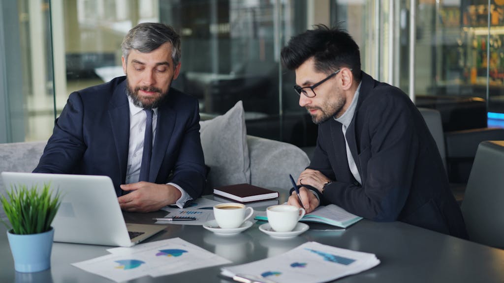 SME Growth Loan Two business men sitting at a table with a laptop Tax Planning and Tax Compliance